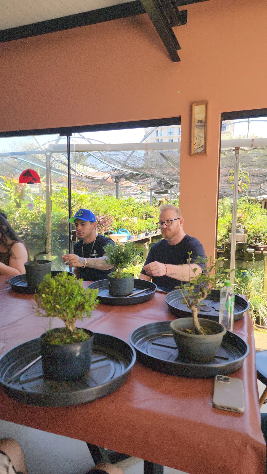 Participantes observando e trabalhando suas plantas na bancada.